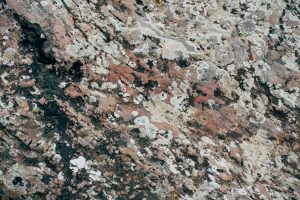 A picture of a portion of granite countertop. The primary colors are black, dusty red, and light gray.